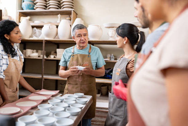 istock Teacher talking to a group of students in a pottery class 1729966385