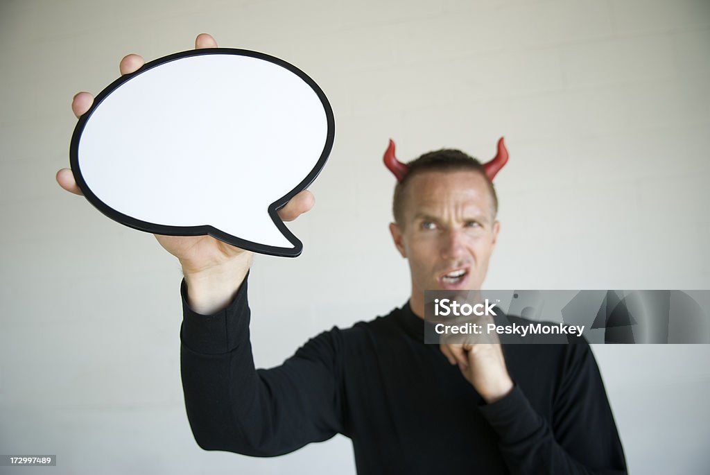 Speech Bubble with a Devil Guy Large cartoonish speech bubble dominates the frame in front of a guy with red devil horns and a mischievous expression Adult Stock Photo