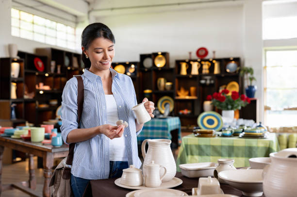 Happy Latin American woman shopping at a pottery store and looking at a jar while smiling - small business concepts