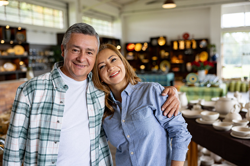 Portrait of a happy Latin American couple shopping at a pottery store and looking at the camera smiling