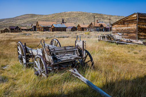 Scenic view of old rusted equipment on blooming landscape near abandoned wooden building at Bodie State Historic Park.