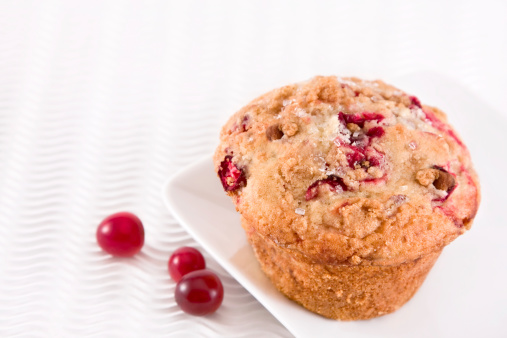 Cranberry muffin on white textured background - shallow depth of field.