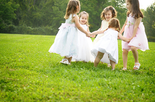 Color photo of five little princesses playing in the grass.