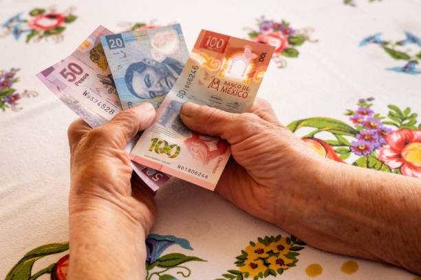 istock Mexican money, a pensioner holds several pesos banknotes in her hand, Financial problems of seniors, low pensions in Mexico 1730004756