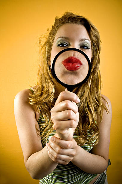 Big kiss Attractive woman sending kiss through magnifying tool. She is on orange background. georgijevic stock pictures, royalty-free photos & images