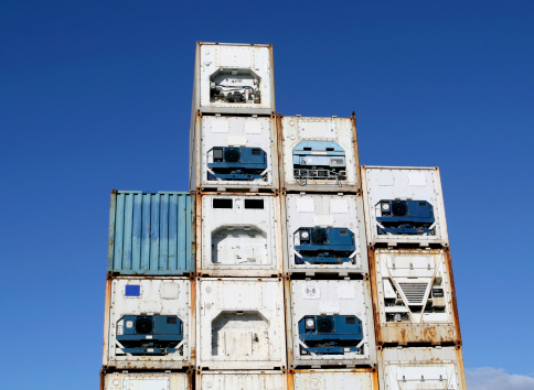 Stack of refrigerated shipping containers at a freight terminal.