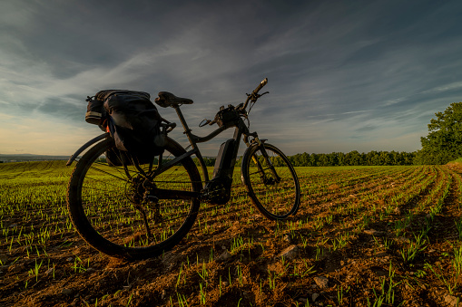 Electric black and gray bicycle on green field with sunset colors near Ceske Budejovice city