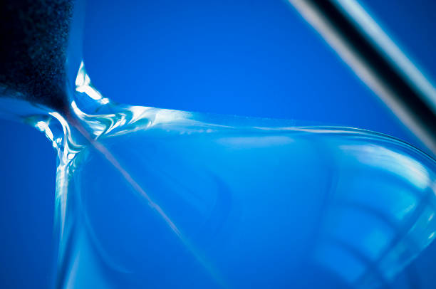 Close view of sand flowing through an hourglass.