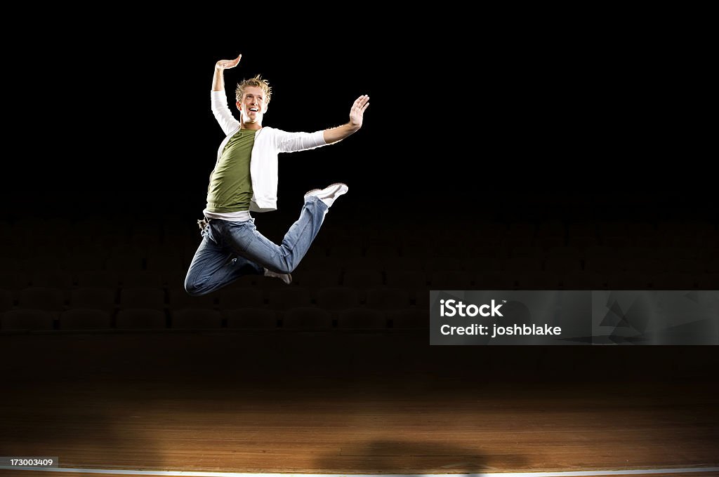 leaping on stage male dancer leaps in the air on wooden stage Black Background Stock Photo