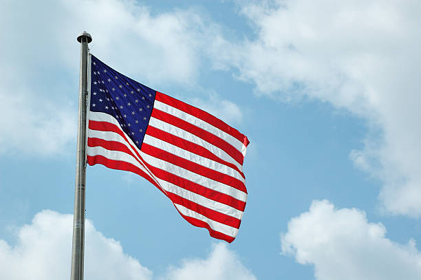 istock American Flag Waving in Breeze with Clouds 173003943