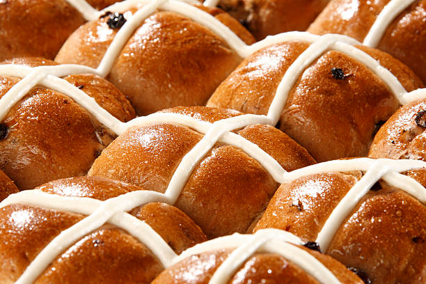 A close up shot of freshly baked hot cross bun on white background.