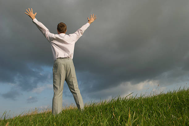 istock Man Holds Hands Up Against Dark Sky 173005407