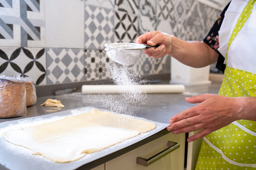 Woman sprinkling flour on the cake batter in a bakery kitchen