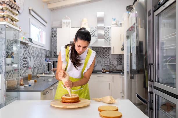 istock Woman decorating a cake in the kitchen of a bakery 1730056921