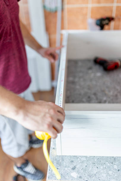 istock Man working on a new kitchen shelf installation and using a tape measure. Home improvement concept. 1730078843