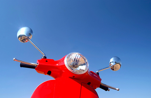 Red retro vespa against blue summer sky