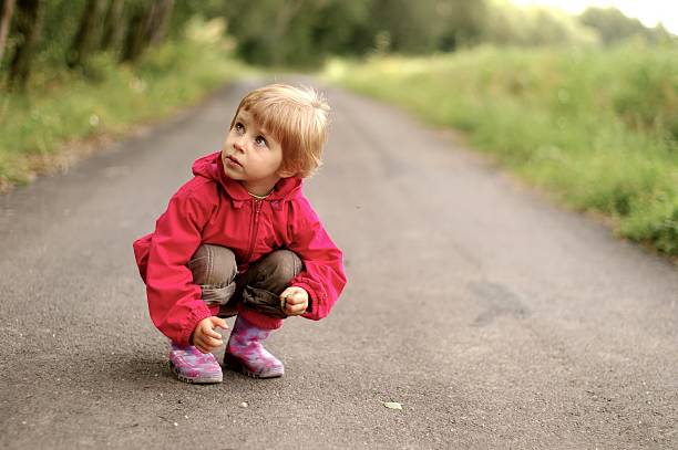 istock Little girl in boots crouching on a road 173008459