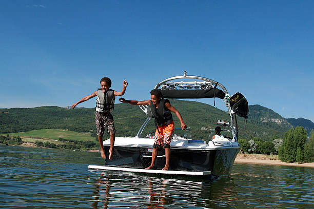 garçons jouant sur le bateau - life jacket little boys lake jumping photos et images de collection