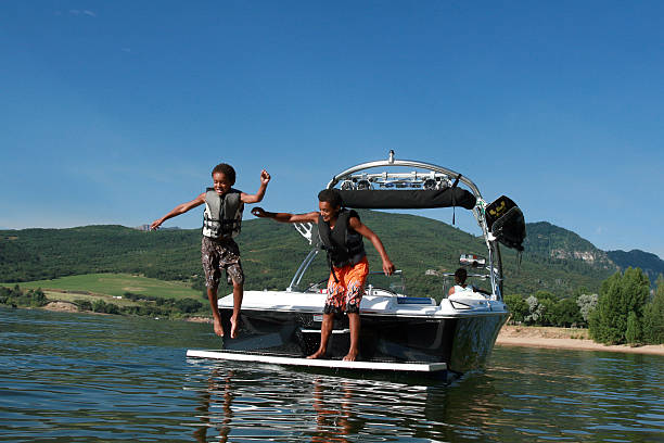 Boys Playing on the boat "Two boys playing on the back of the boat, jumping into the water" boat on lake stock pictures, royalty-free photos & images