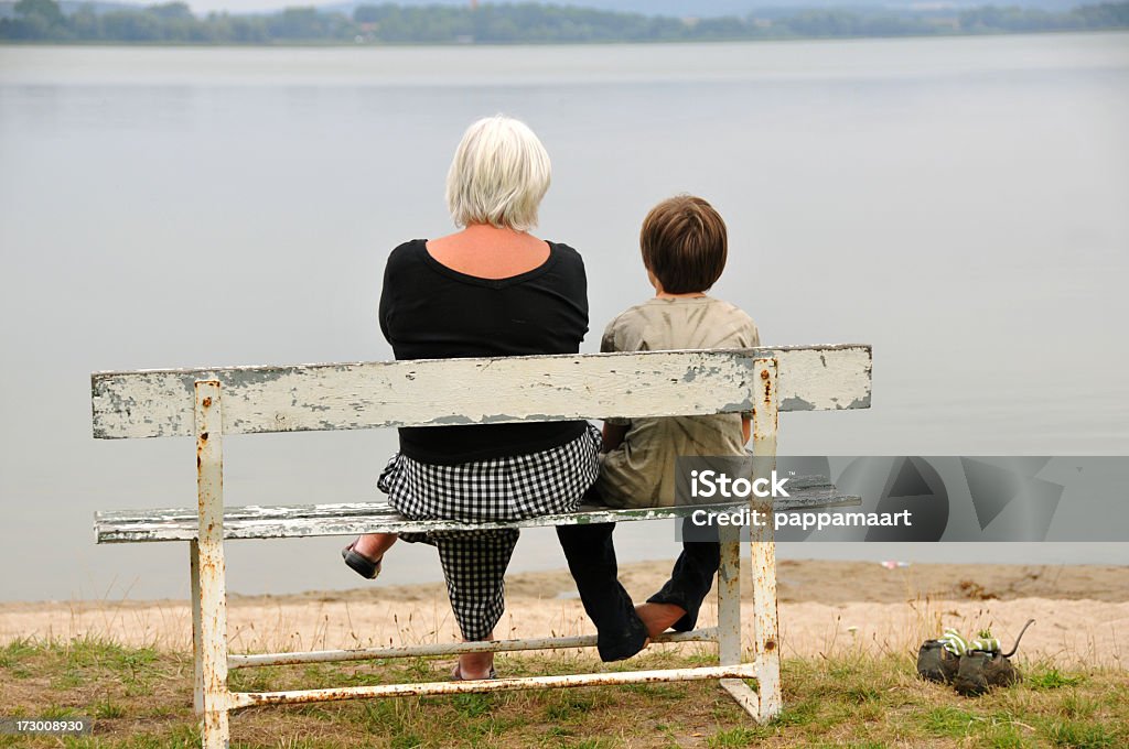 Бабушка и Внук, сидящая на скамье на озеро - Стоковые фото Вид сзади роялти-фри