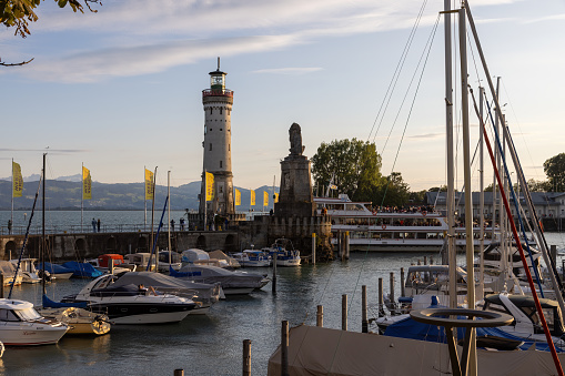 Lindau, Germany August 05 2023: Lindau, with a view of an excursion boat and the harbor entrance with a lighthouse and lion