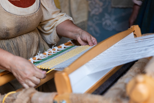 a woman spinning wool by hand with an old spindle