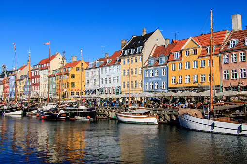 Nyhavn canal with its colorful houses on a clear day with blue sky in Copenhagen, Denmark