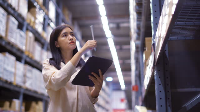 Female worker checking products with tablet in warehouse.