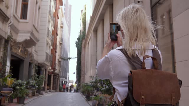 Tourist takes pictures of old town street with mobile smartphone camera