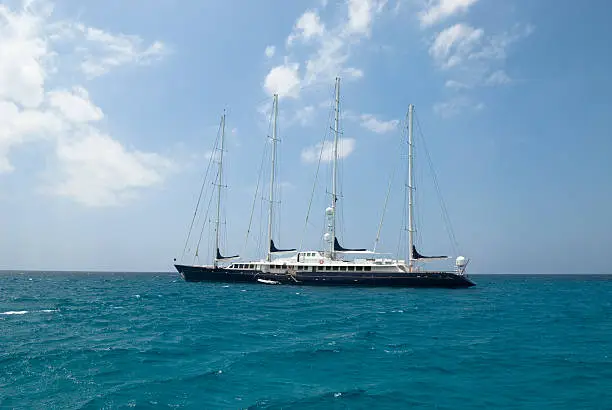 A luxurious sailing yacht anchoring in the Mediterranean.