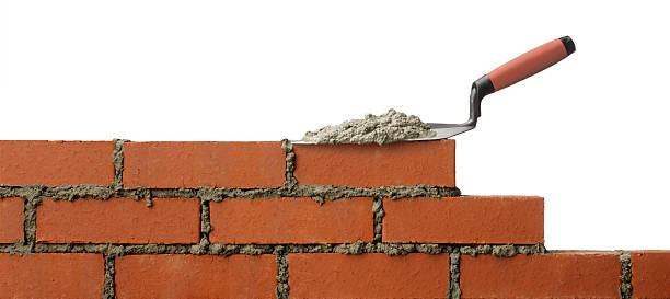 Mortar on trowel sitting on unfinished brick wall