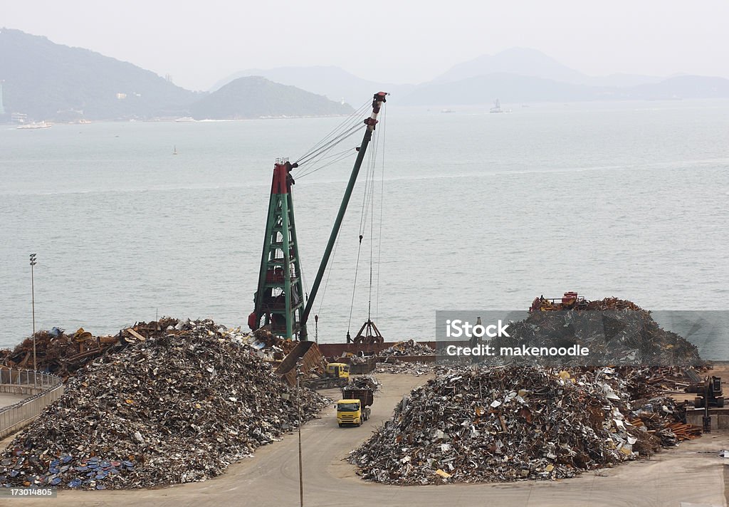 Harbor Scrapyard Harbor metal scrapyard in Hong Kong with onboard grabber loading/unloading onto trucks. Garbage Stock Photo