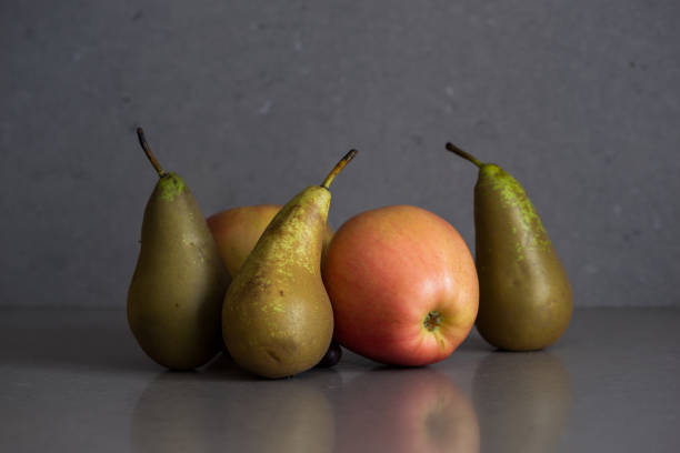 Yellow bananas, green pear and red apple on black background