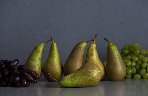 Autumn fruit still life with pears and grapes on the grey background