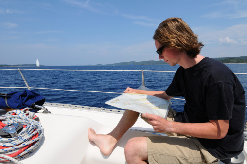 Young male skipper working on sea chart