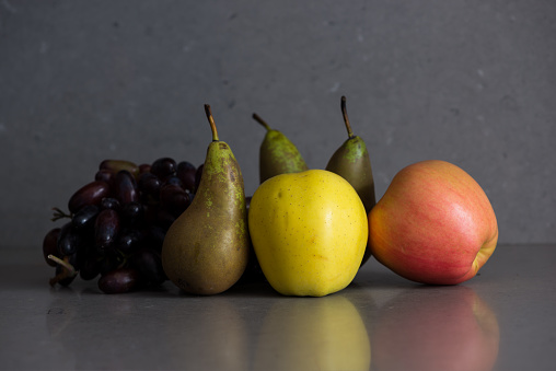 Autumn fruit still life with pears, apples and grapes on the grey background