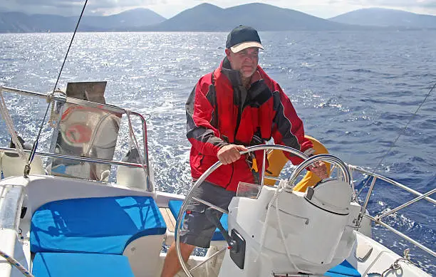 helmsman at wheel of modern cruising yacht in greek ionian sea