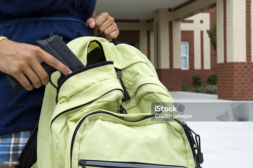 school vioence student pulling out a gun in front of a school building.  Please view all these along with all Gun Stock Photo