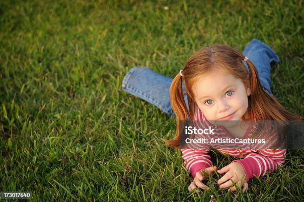 Foto de Feliz Pouco Cabelo Ruivo Menina Deitada Na Grama e mais fotos de stock de 2-3 Anos - 2-3 Anos, Aluno de Jardim de Infância, Cabelo Ruivo