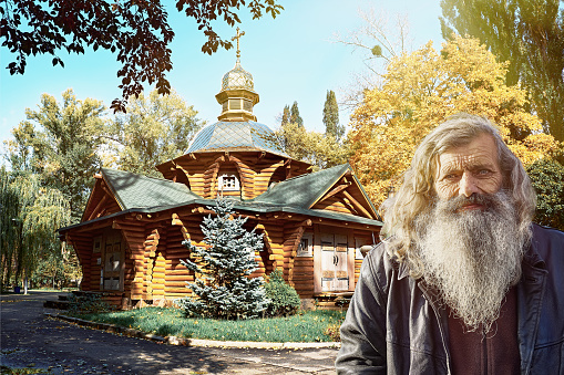 Wisdom stands the test of time. An elderly man beside a wooden church, embodying the timeless grace of age and heritage.