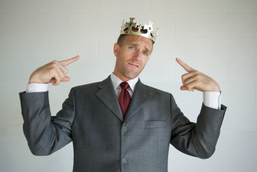 Businessman pointing with a bit of attitude to the golden crown on his head as if he thinks he's the king
