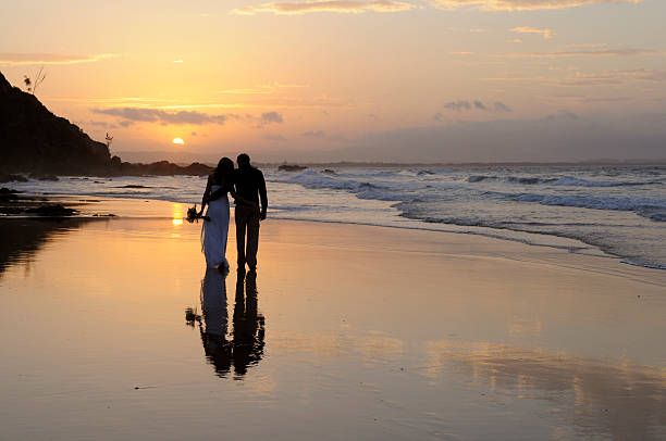 A newly married couple walking away together on the beach