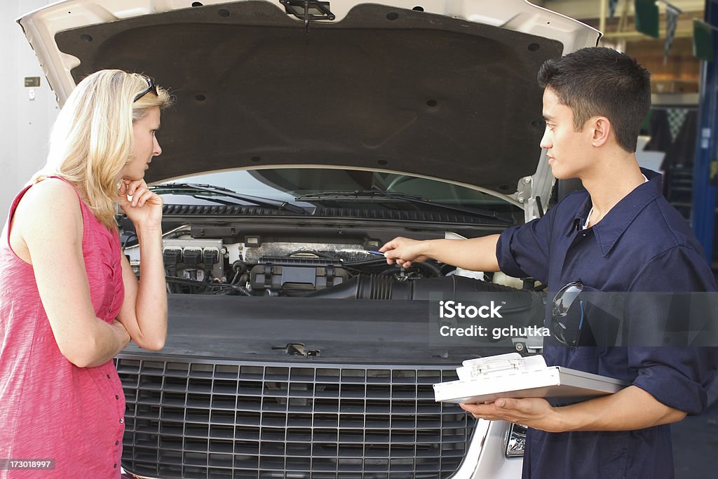 Car Repair Auto mechanic reviews necessary repairs with a female customer. 20-29 Years Stock Photo