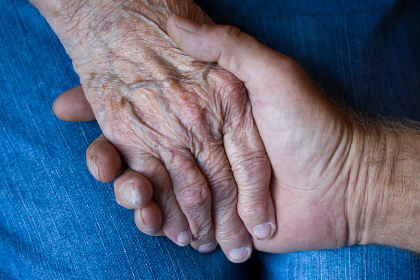 Elderly Mother's Hand Held By Son stock photo