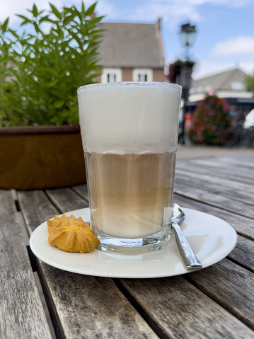 Caffe latte macchiato coffee layered with milk with a cookie