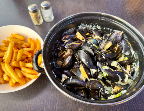 Pan of moules mariniere with a bowl of French fries
