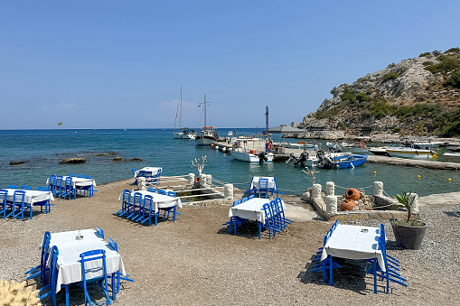 Typically Greek blue restaurant table and chairs beside the sea - Image taken in the harbour are of Kolimbia, Rhodes, Greece