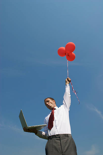 homem de negócios com computador portátil guarda balões - computer humor stranded business imagens e fotografias de stock