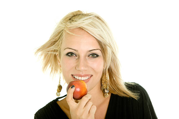 Teenage smiling girl holds a red apple with her hands and offers it at camera