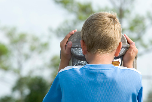 Shown here is a close up of a seven year old boy using a pair of mounted binoculars.See other related images here: